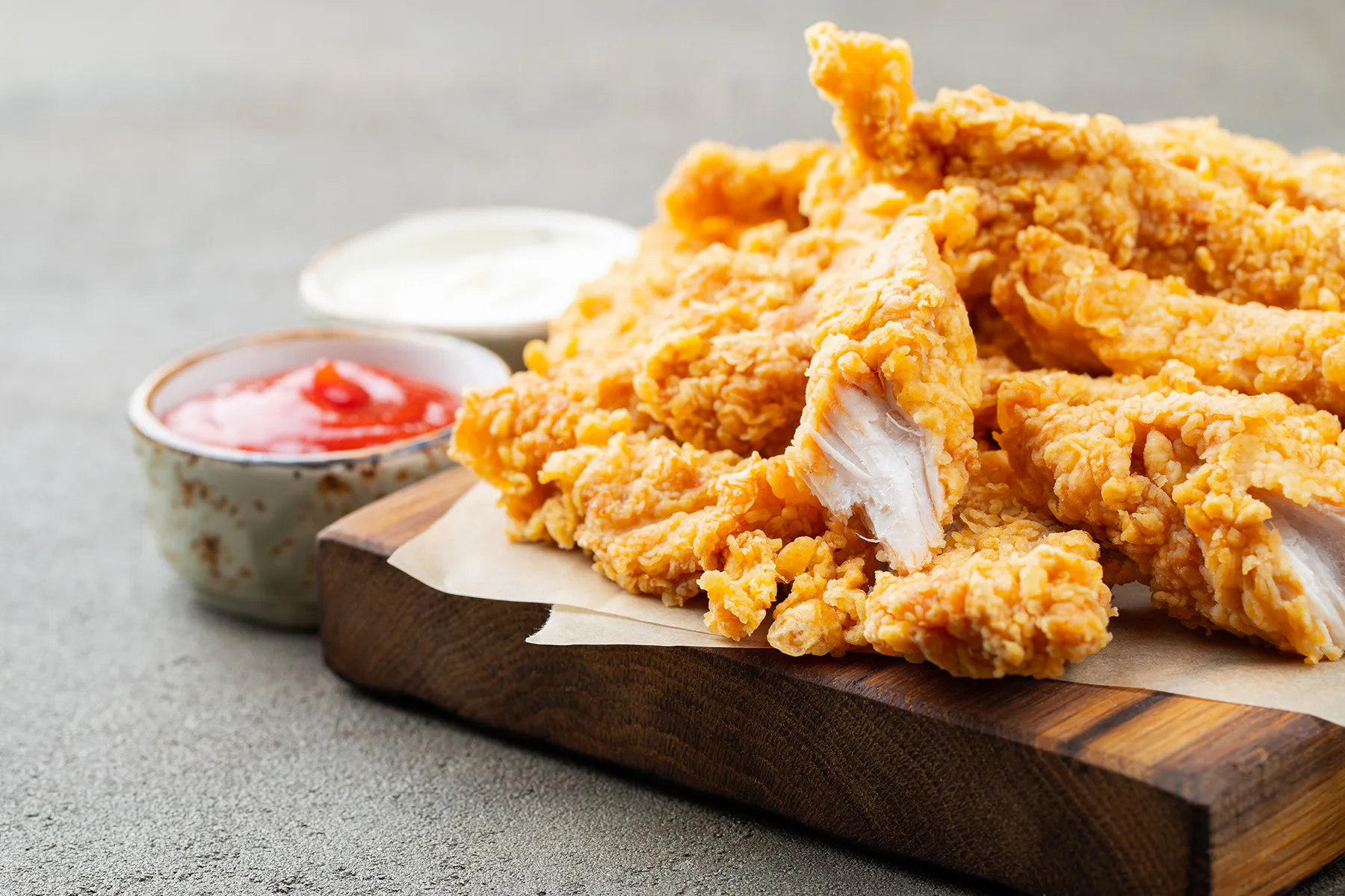 Crunchy fried chicken tenders with ketchup and creamy sauce